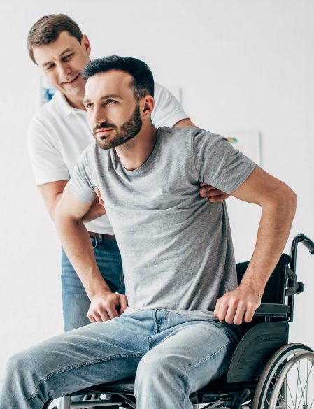 Physiotherapist helping handicapped man in Wheelchair during recovery in hospital